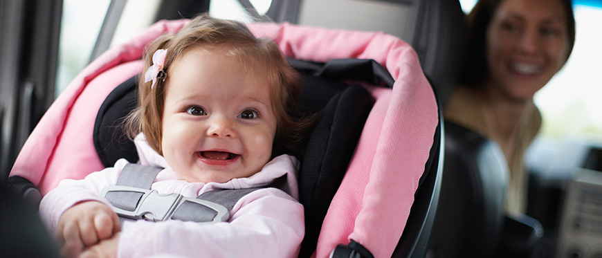 A toddler in a car seat with her mom looking back at her