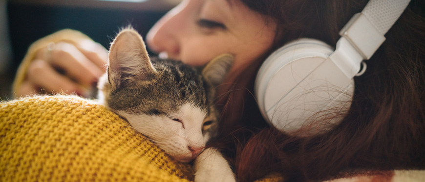 Woman with headphones on snugging a kitten