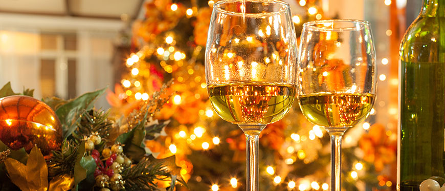 Two glasses of white wine and wine bottle on table in front of christmas tree