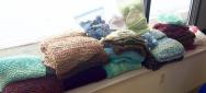 Stacks of shawls, afghans, lap robes, hats, blankets, and stress balls knitted for patients